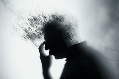 black and white photo image of person resting head in hand, very blurred, with abstract shapes flowing into or out of forehead