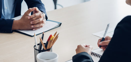 close up of 2 people across desk cropped to show hands only, in course of interview