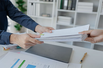 person handing files to another person 