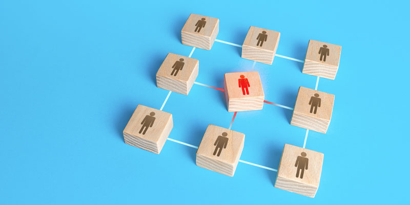 group of wooden blocks with human forms of front arranged in square around block with red human form on it