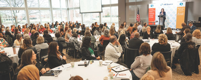 Conference event photo of audience with Mary Lynn Fayoumi speaking in background