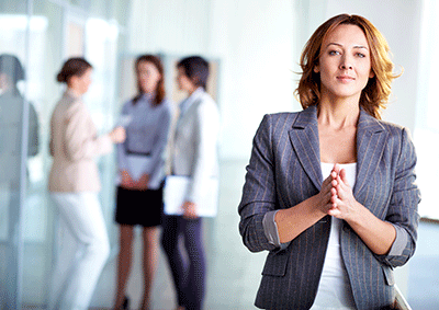 business women, office setting, looking at camera, other employees in blurred background